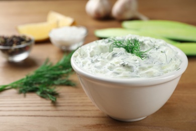 Photo of Cucumber sauce with ingredients on wooden background, space for text. Traditional Tzatziki