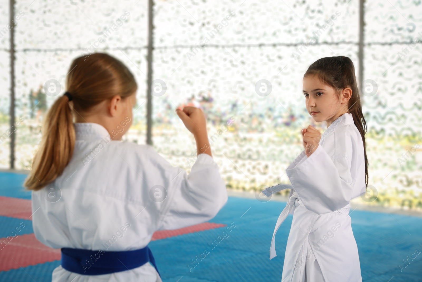 Photo of Children in kimono practicing karate on tatami outdoors