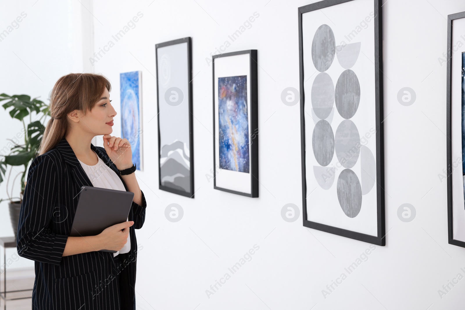 Photo of Thoughtful young woman with tablet at exhibition in art gallery