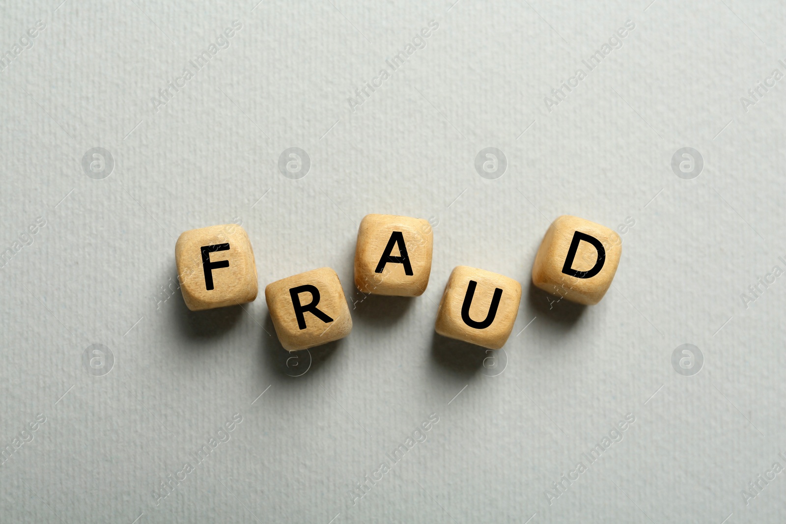 Photo of Word Fraud of wooden cubes with letters on light  grey background, flat lay