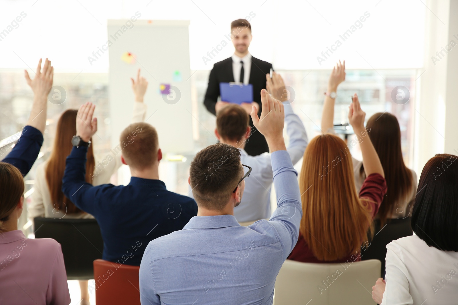 Photo of People raising hands to ask questions at business training indoors