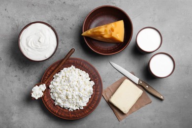 Clay dishware with fresh dairy products on grey table, flat lay