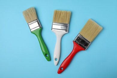 Photo of Paint brushes on color background, top view
