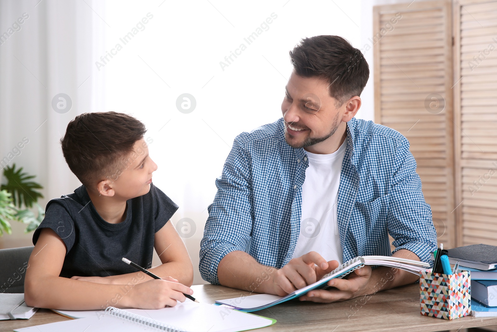 Photo of Dad helping his son with homework in room