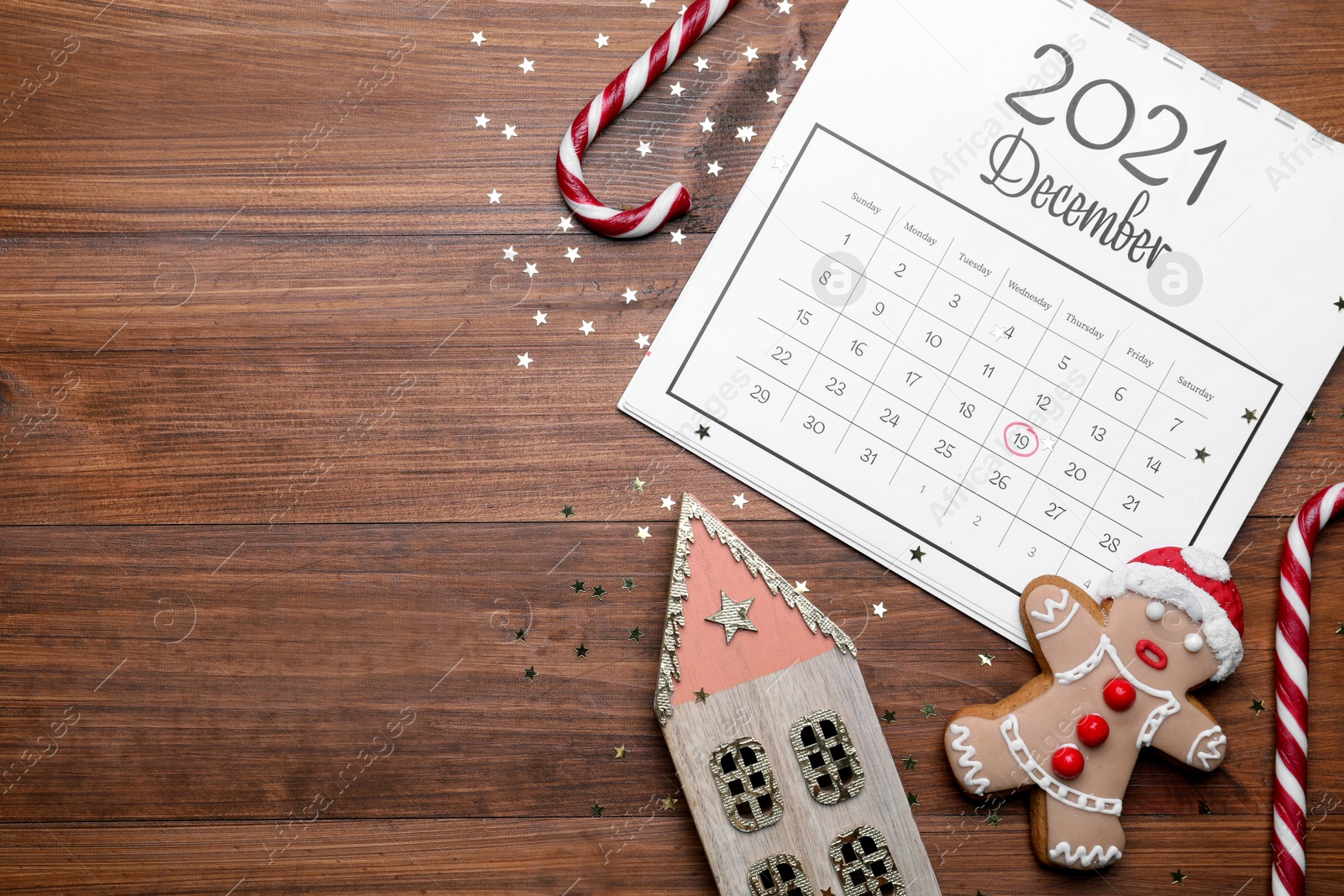 Photo of Saint Nicholas Day. Calendar with marked date December 19, sweets and festive decor on wooden table, flat lay. Space for text