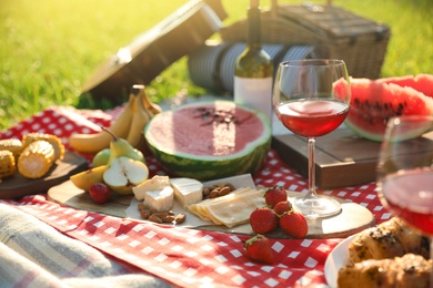 Photo of Picnic blanket with delicious food and drinks outdoors on sunny day