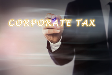 Image of  Corporate tax concept. Man writing on virtual screen against color background, closeup