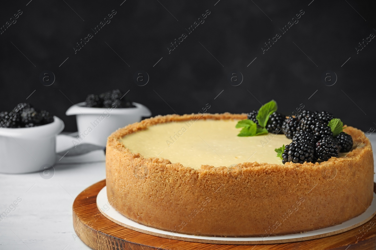 Photo of Delicious cheesecake decorated with blackberries on table