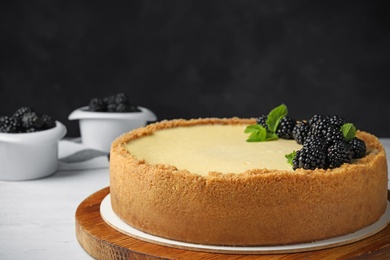 Delicious cheesecake decorated with blackberries on table