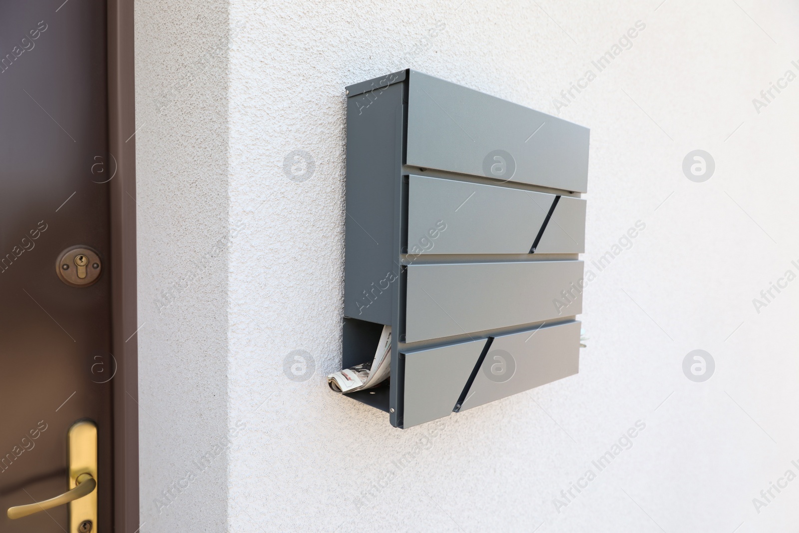 Photo of Grey metal letter box on white wall near entrance