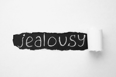 Word JEALOUSY under ripped paper as background, top view