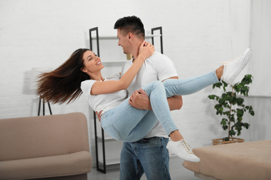 Happy young couple dancing together at home