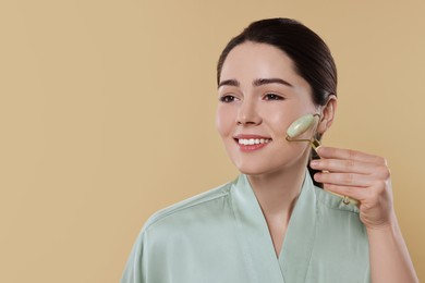Photo of Young woman massaging her face with jade roller on beige background. Space for text
