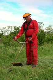 Photo of Worker cutting grass with string trimmer outdoors