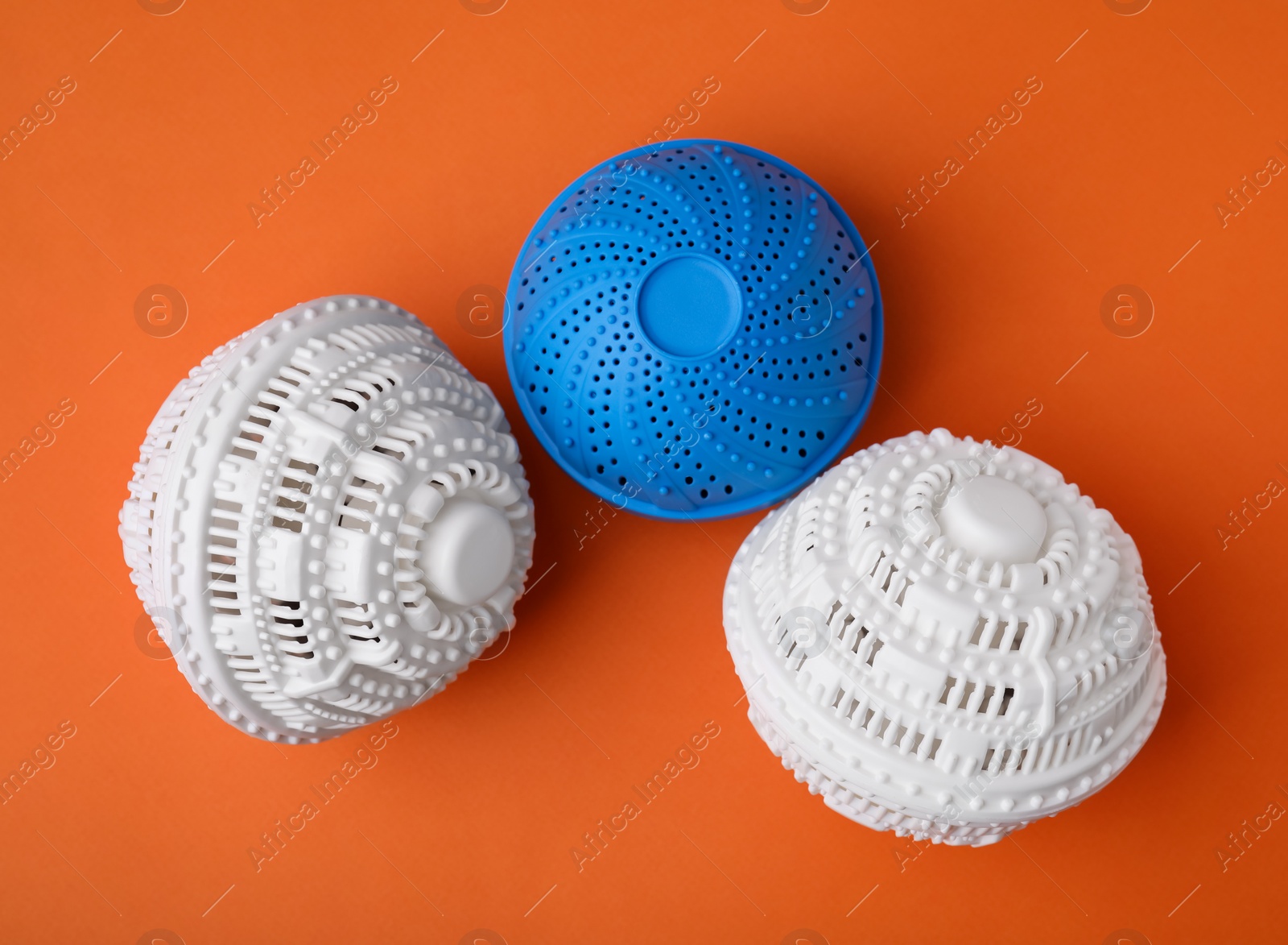 Photo of Dryer balls for washing machine on orange background, flat lay