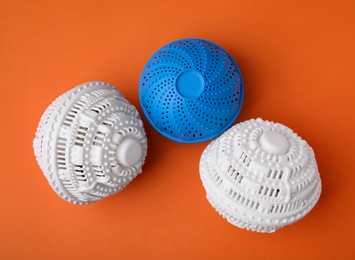 Photo of Dryer balls for washing machine on orange background, flat lay