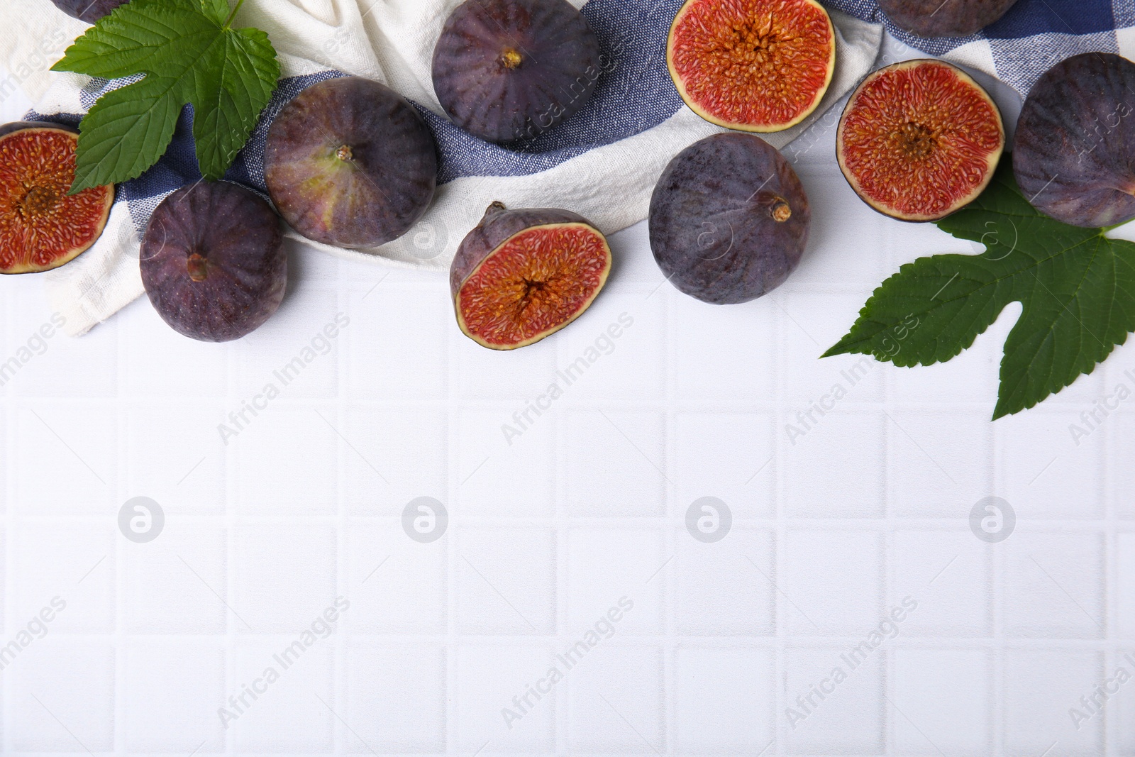 Photo of Fresh ripe purple figs on white tiled table, flat lay. Space for text