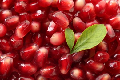 Photo of Green leaves on ripe juicy pomegranate grains, top view