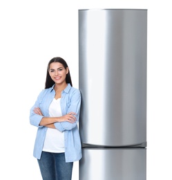 Young woman near closed refrigerator on white background