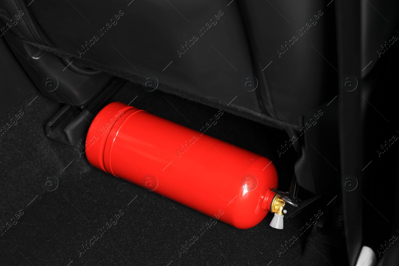 Photo of Red fire extinguisher in trunk. Car safety equipment