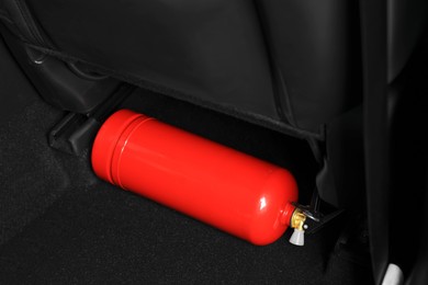 Photo of Red fire extinguisher in trunk. Car safety equipment