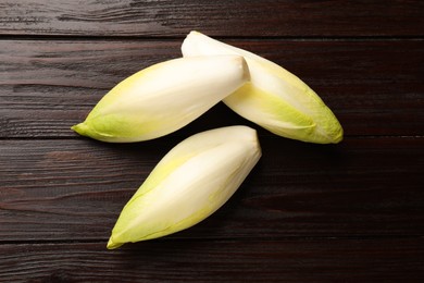 Photo of Raw ripe chicories on wooden table, top view