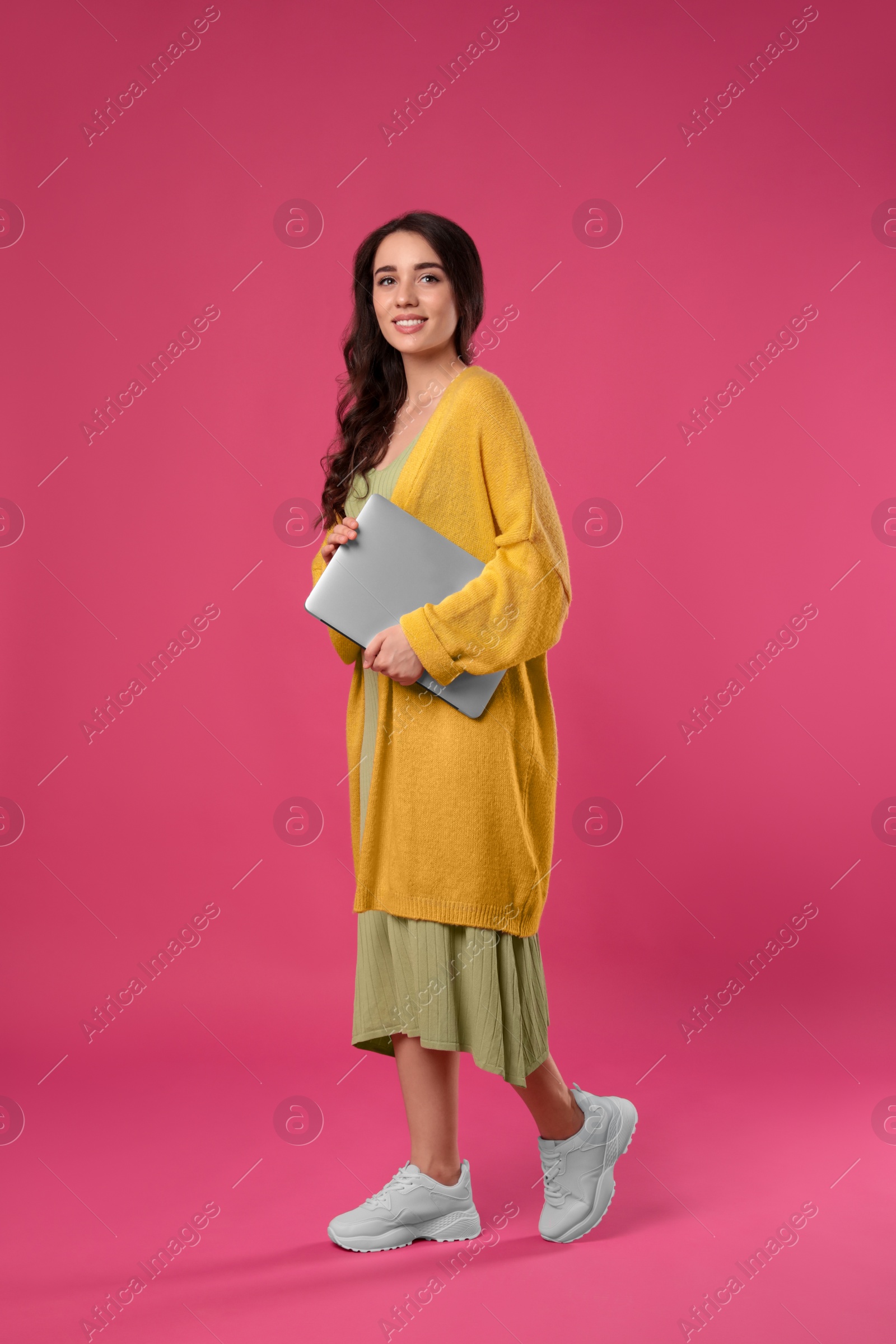 Photo of Young woman with laptop on pink background