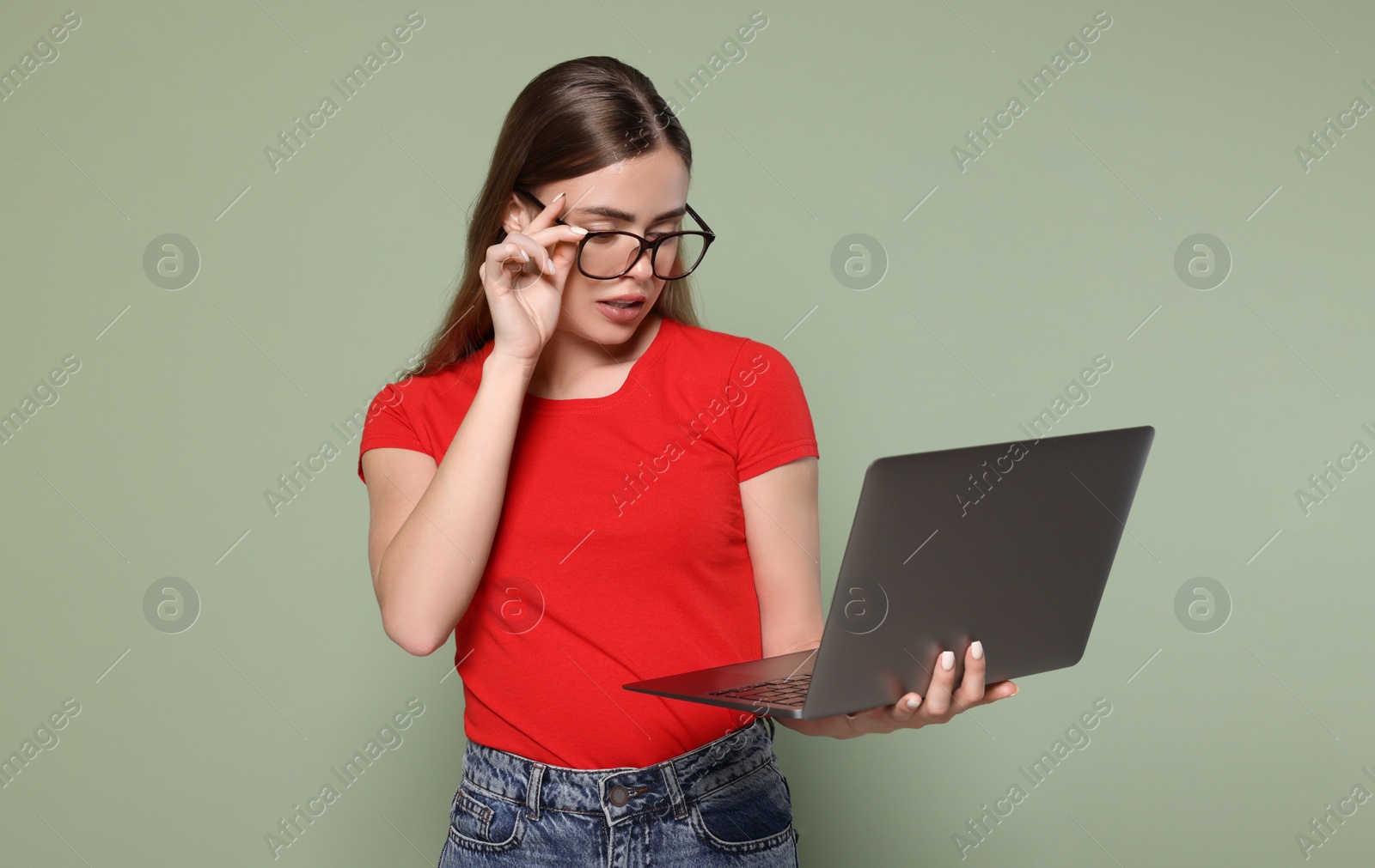 Photo of Beautiful woman in glasses with laptop on pale green background