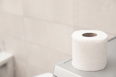Photo of Toilet paper roll on table in bathroom. Space for text