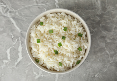 Photo of Bowl with tasty cooked rice on light grey marble table, top view