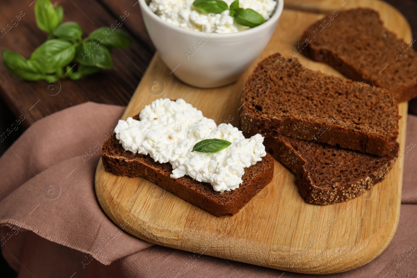 Photo of Bread with cottage cheese and basil on table