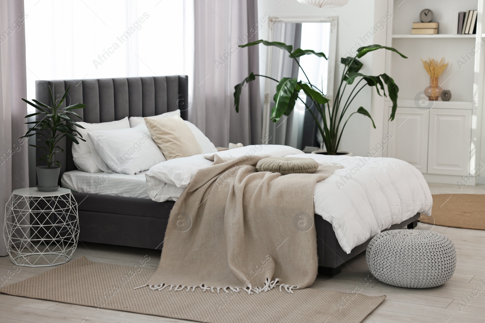 Photo of Soft beige plaid on bed in stylish bedroom. Interior design