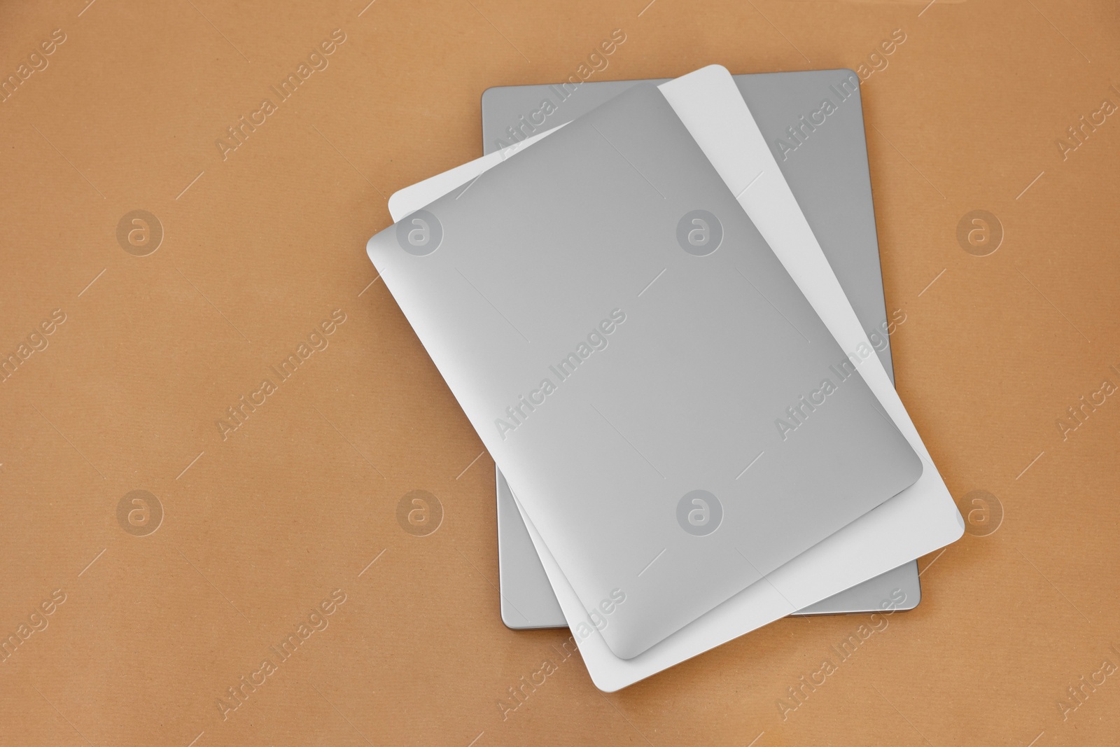 Photo of Different modern laptops on brown background, top view