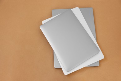 Photo of Different modern laptops on brown background, top view