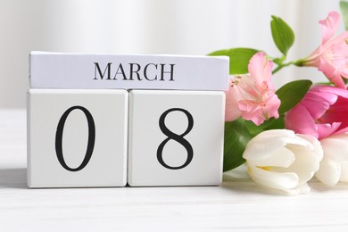 International Women's day - 8th of March. Wooden block calendar and beautiful flowers on white table