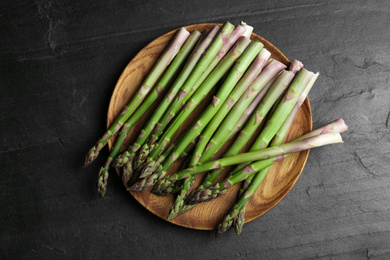 Photo of Fresh raw asparagus on black table, top view