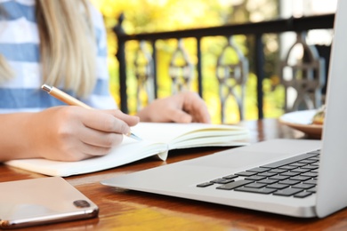 Photo of Woman writing blog content in notebook at table, closeup