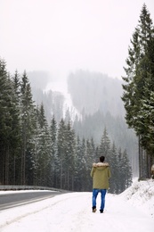 Man walking near snowy forest on winter day