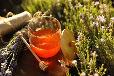 Jar of honey on wooden table in lavender field. Space for text