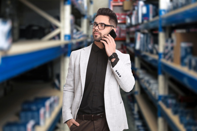 Image of Wholesale and logistics concept. Manager talking on phone in warehouse