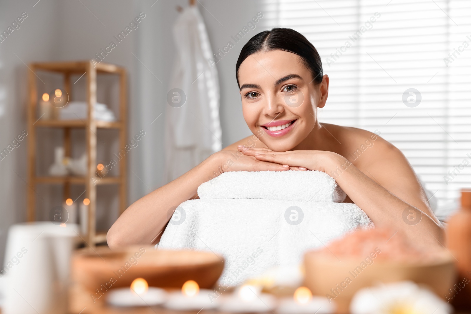 Photo of Beautiful happy woman relaxing on massage table in spa salon