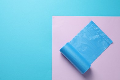 Roll of turquoise garbage bags on color background, top view. Space for text