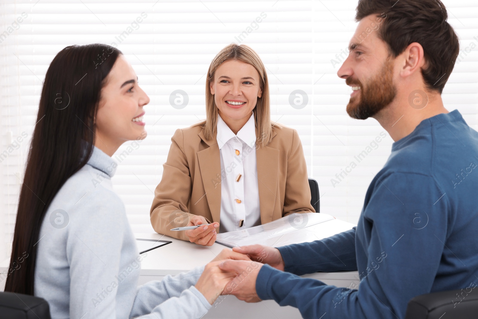 Photo of Real estate agent working with couple in office