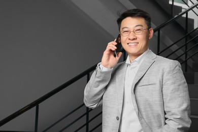 Photo of Happy boss talking on phone in office. Space for text