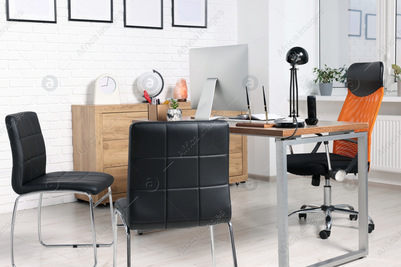 Photo of Stylish director's workplace with comfortable desk, computer and chairs for visitors in office. Interior design