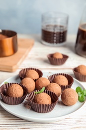 Photo of Plate with chocolate truffles on wooden table