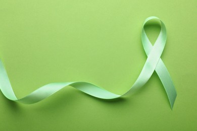Photo of World Mental Health Day. Green ribbon on color background, top view with space for text