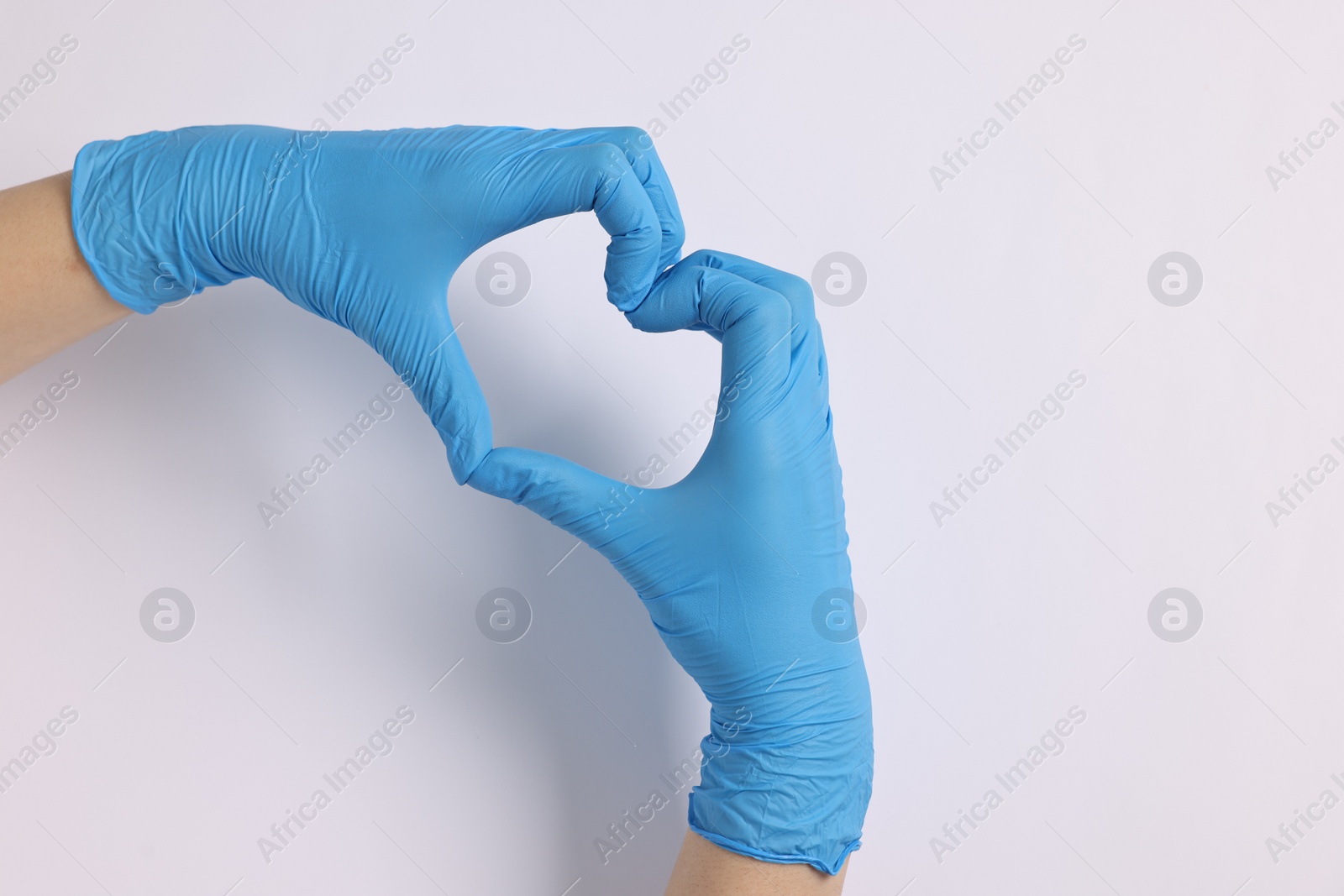 Photo of Doctor showing heart gesture with hands on white background, top view. Space for text