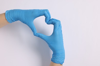 Photo of Doctor showing heart gesture with hands on white background, top view. Space for text