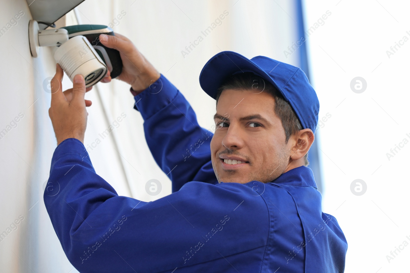 Photo of Technician installing CCTV camera on wall outdoors